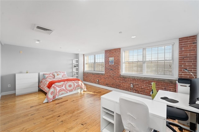 bedroom featuring brick wall and light hardwood / wood-style floors