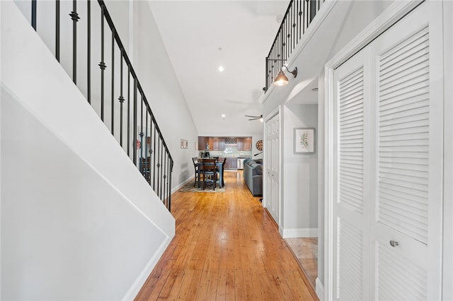 hallway with light wood-type flooring and a high ceiling