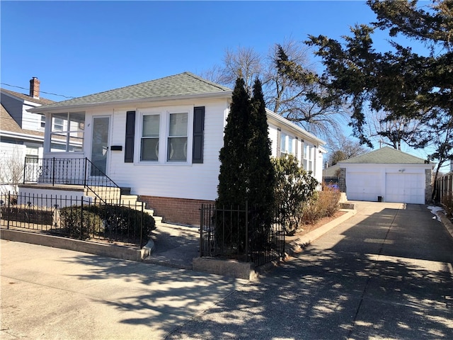 view of front of property with a garage, an outbuilding, roof with shingles, and fence