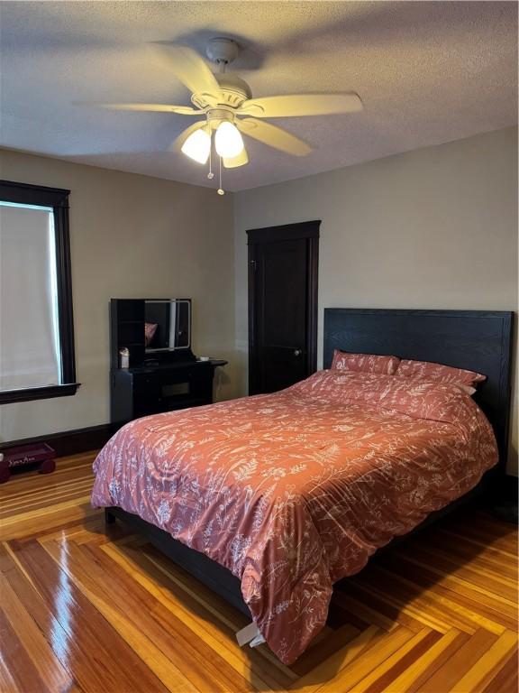 bedroom featuring a ceiling fan, a textured ceiling, and baseboards