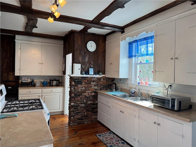 kitchen with dark wood finished floors, light countertops, white cabinets, a sink, and white range with gas cooktop