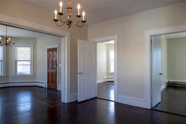 spare room with a baseboard heating unit, dark hardwood / wood-style floors, and an inviting chandelier