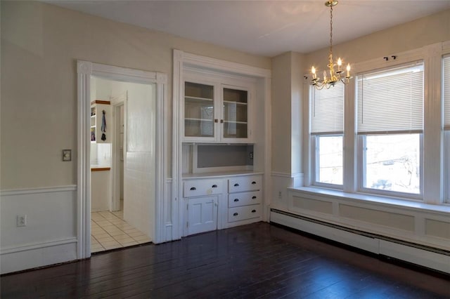 unfurnished dining area with baseboard heating, dark hardwood / wood-style floors, and a notable chandelier