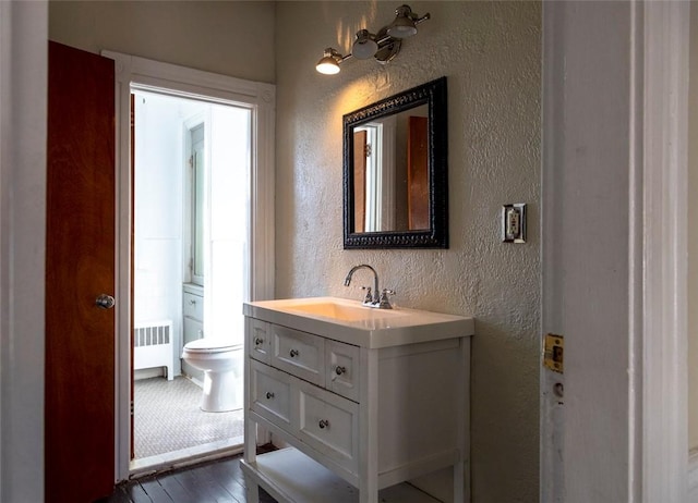 bathroom featuring radiator, wood-type flooring, vanity, and toilet