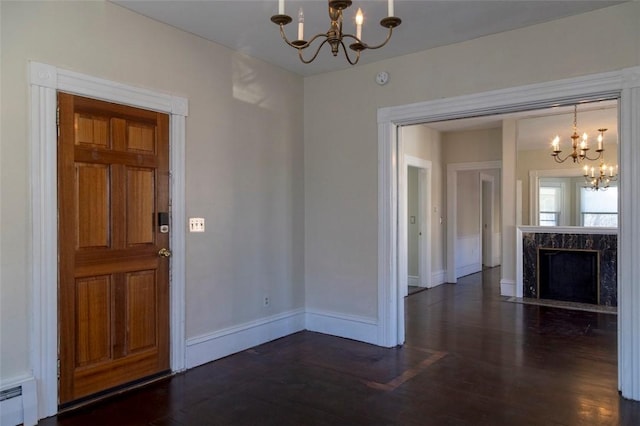 entrance foyer with a baseboard heating unit, a high end fireplace, an inviting chandelier, and dark hardwood / wood-style flooring