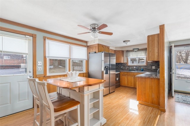 kitchen with appliances with stainless steel finishes, decorative backsplash, light hardwood / wood-style floors, and ceiling fan