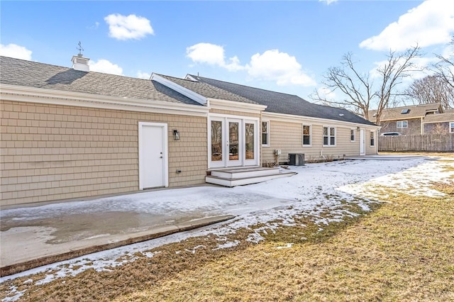 snow covered house with central AC unit and french doors