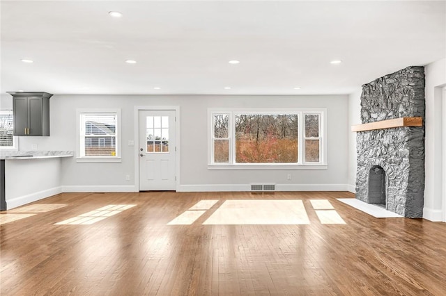 unfurnished living room featuring hardwood / wood-style flooring, a wealth of natural light, and a fireplace