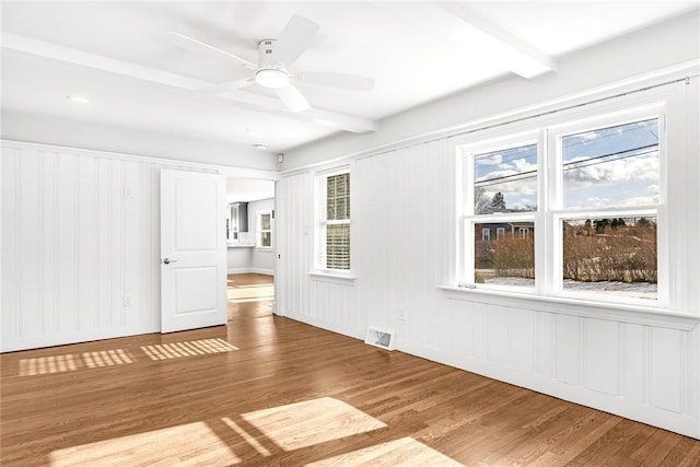 unfurnished room with ceiling fan, beamed ceiling, and hardwood / wood-style floors