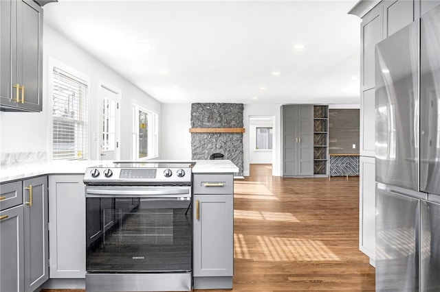 kitchen with gray cabinets, stainless steel appliances, dark wood-type flooring, and a fireplace