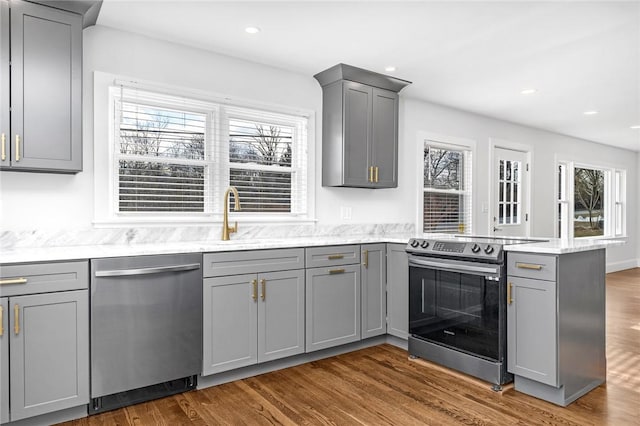 kitchen with appliances with stainless steel finishes, gray cabinetry, sink, dark hardwood / wood-style floors, and kitchen peninsula