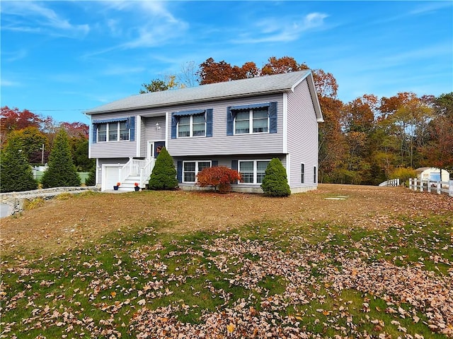 raised ranch featuring a front lawn and a garage