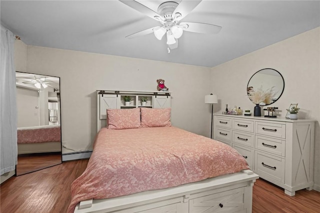 bedroom featuring ceiling fan, a baseboard heating unit, and hardwood / wood-style floors