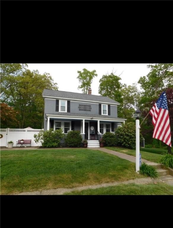 view of front facade featuring a chimney, a front yard, and fence