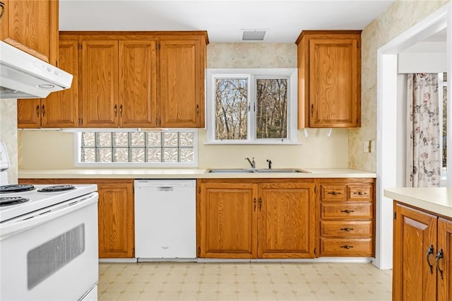 kitchen featuring light floors, white appliances, a sink, and under cabinet range hood