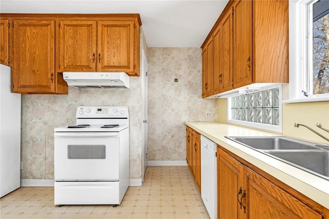 kitchen featuring white appliances, under cabinet range hood, light floors, and wallpapered walls