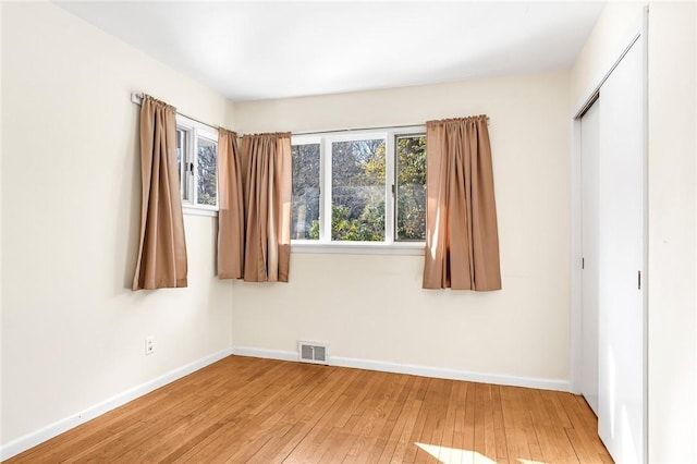 unfurnished bedroom with a closet, visible vents, light wood-style flooring, and baseboards