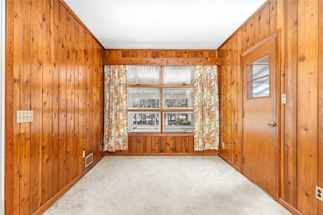 unfurnished room with wood walls, carpet, and visible vents