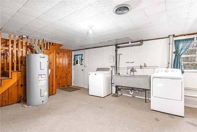 below grade area featuring wooden walls, visible vents, washer and clothes dryer, electric water heater, and a sink