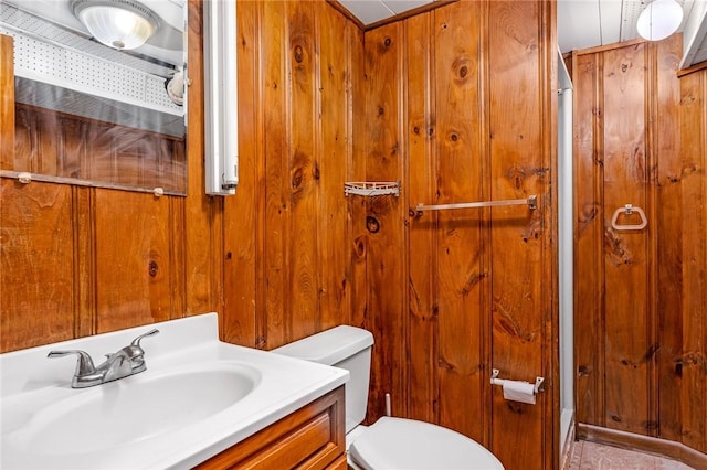 bathroom with toilet, wooden walls, and vanity