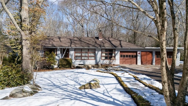 ranch-style house featuring a garage, driveway, and a chimney