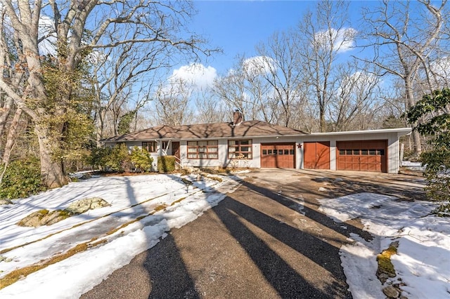 view of front of home featuring driveway, an attached garage, and a chimney