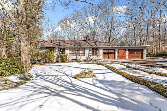 view of front of house with an attached garage, driveway, and a chimney