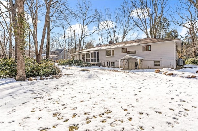 snow covered property featuring cooling unit, a sunroom, and a chimney