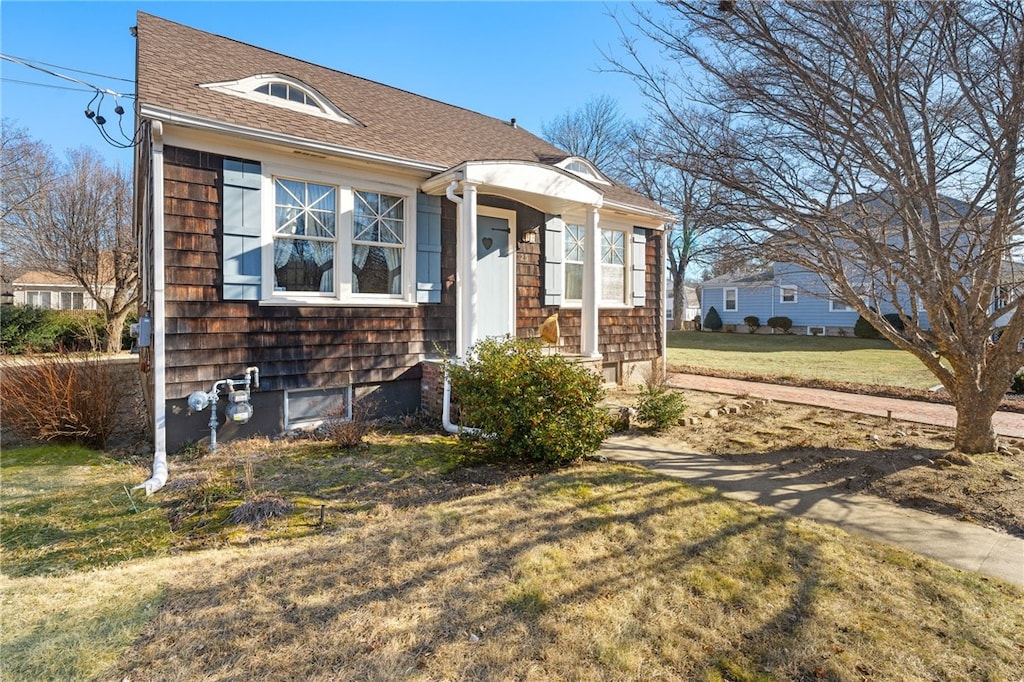 view of front of home featuring a shingled roof and a front yard