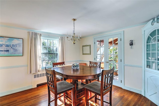 dining room with french doors, ornamental molding, wood finished floors, and an inviting chandelier