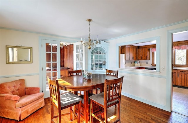 dining area featuring a chandelier, ornamental molding, and wood finished floors