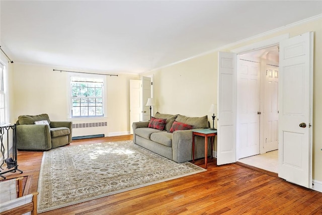 living area with ornamental molding, wood finished floors, and radiator