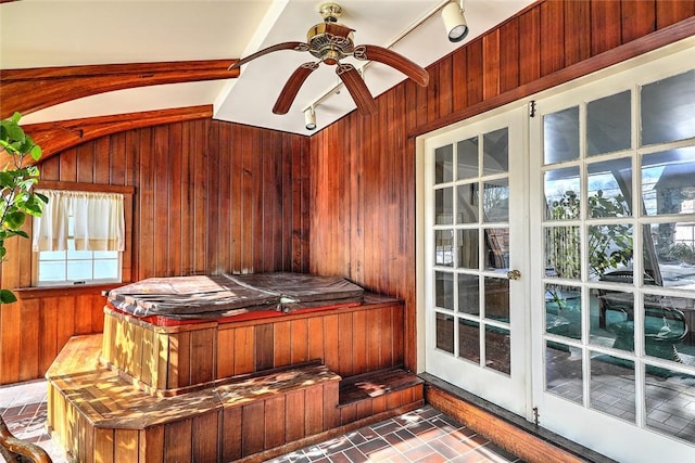 interior space featuring wood walls, vaulted ceiling, brick floor, and a ceiling fan