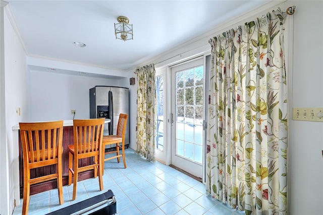 dining space featuring light tile patterned floors and crown molding