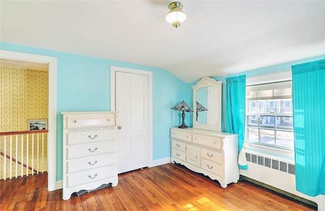 bedroom with wallpapered walls, baseboards, lofted ceiling, dark wood-style floors, and radiator heating unit