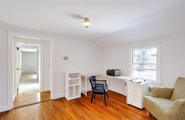 office space with vaulted ceiling, light wood finished floors, a baseboard radiator, and baseboards