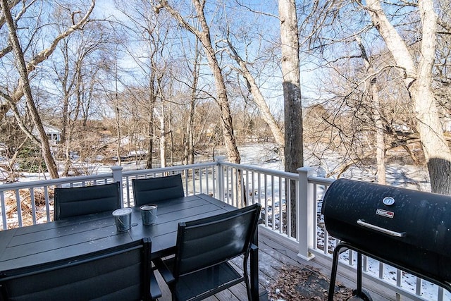 snow covered deck with outdoor dining space and area for grilling