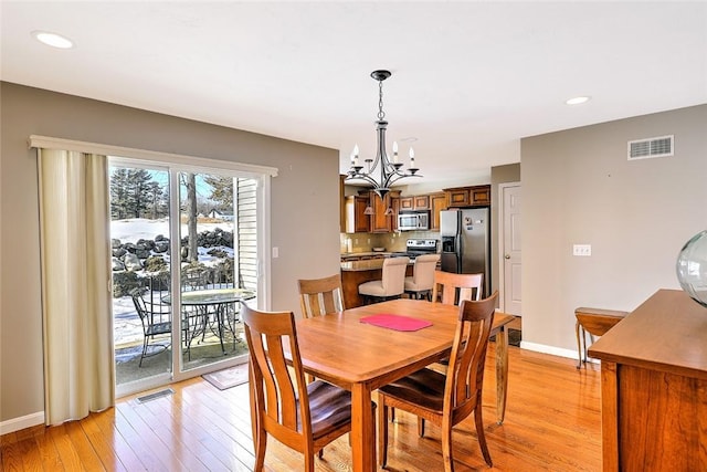 dining room with light wood-style flooring, visible vents, and baseboards