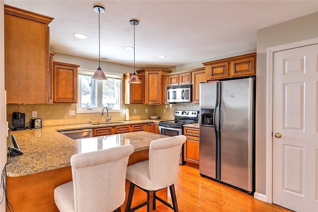 kitchen with stainless steel appliances, a breakfast bar, a sink, and hanging light fixtures