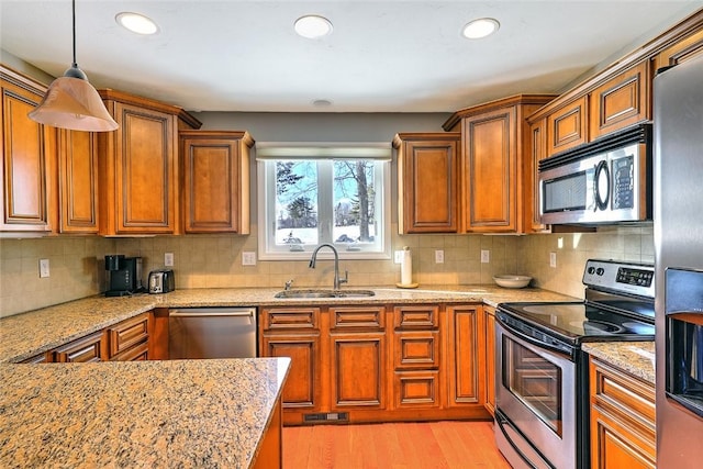 kitchen featuring stainless steel appliances, brown cabinets, and a sink