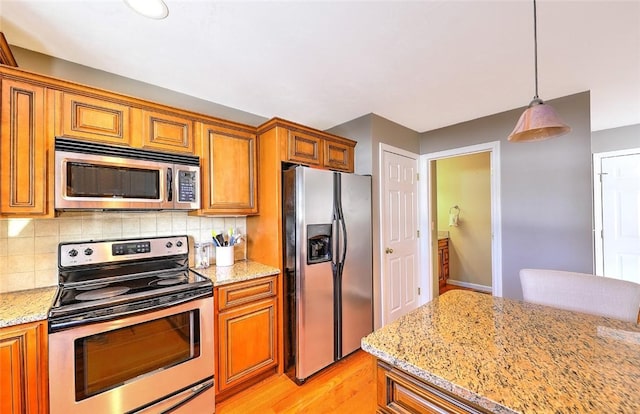 kitchen featuring stainless steel appliances, light stone counters, and tasteful backsplash