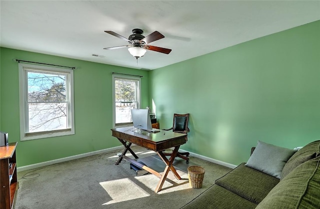 home office with light carpet, a ceiling fan, visible vents, and baseboards