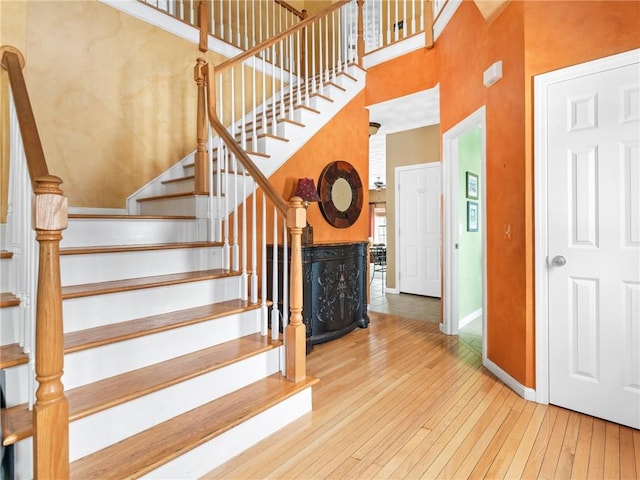 staircase with a high ceiling, baseboards, and wood-type flooring