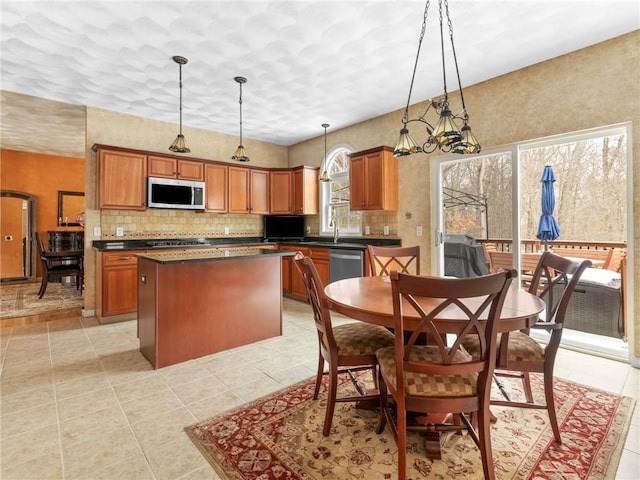 kitchen featuring dark countertops, appliances with stainless steel finishes, a kitchen island, and brown cabinetry