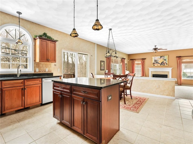 kitchen featuring a sink, decorative light fixtures, a kitchen island, dark countertops, and dishwasher