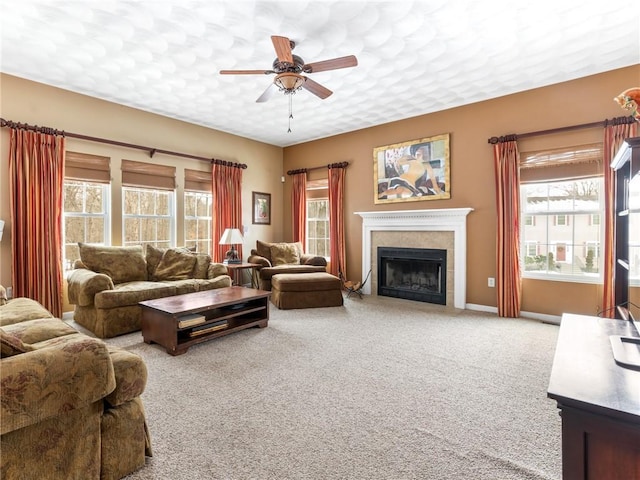 living area with baseboards, ceiling fan, carpet floors, a fireplace, and a textured ceiling