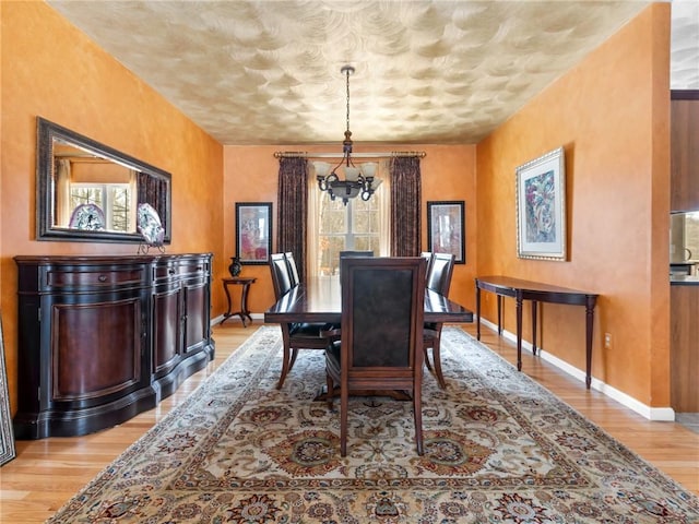 dining area featuring a notable chandelier, baseboards, and light wood-type flooring