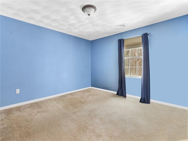 spare room with baseboards, carpet floors, and visible vents