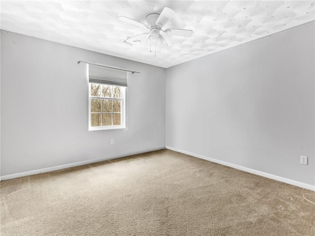 carpeted empty room with ceiling fan and baseboards