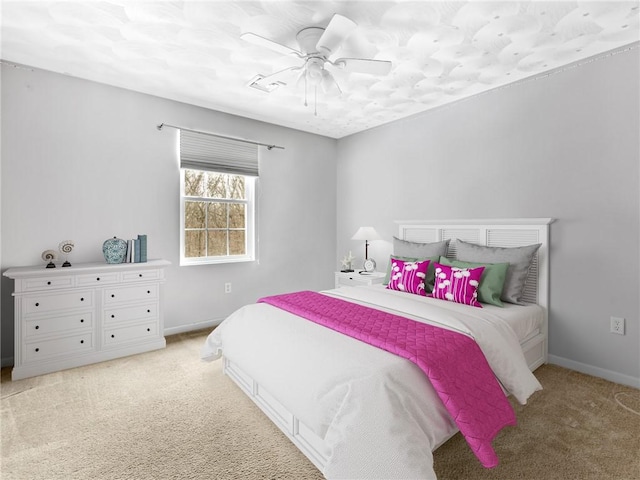 bedroom with visible vents, light colored carpet, baseboards, and ceiling fan